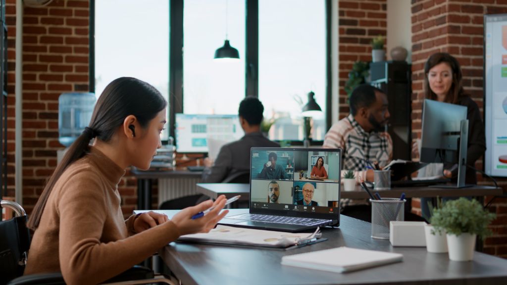 Professional in office joins AI-driven remote team video call, illustrating offshore staffing collaboration