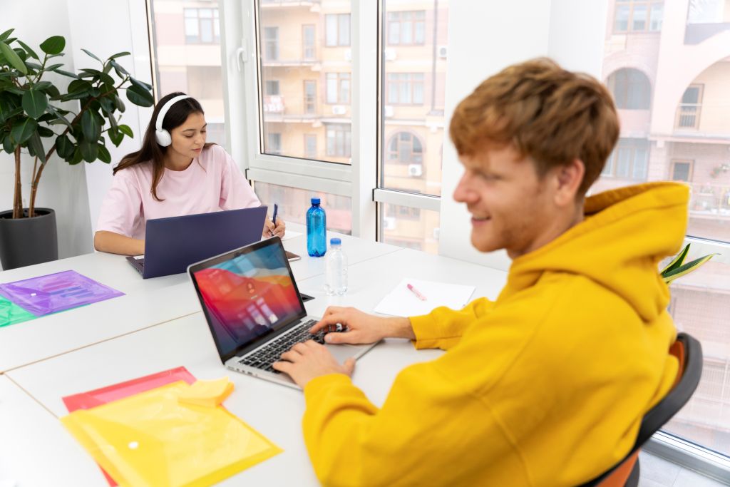 People working on laptops in a bright office, showing a collaborative workspace.